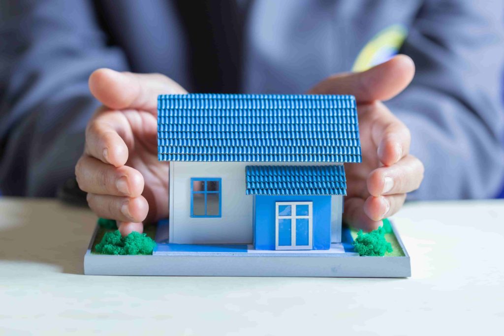 Image d'une maquette de maison étant protégée entre deux mains