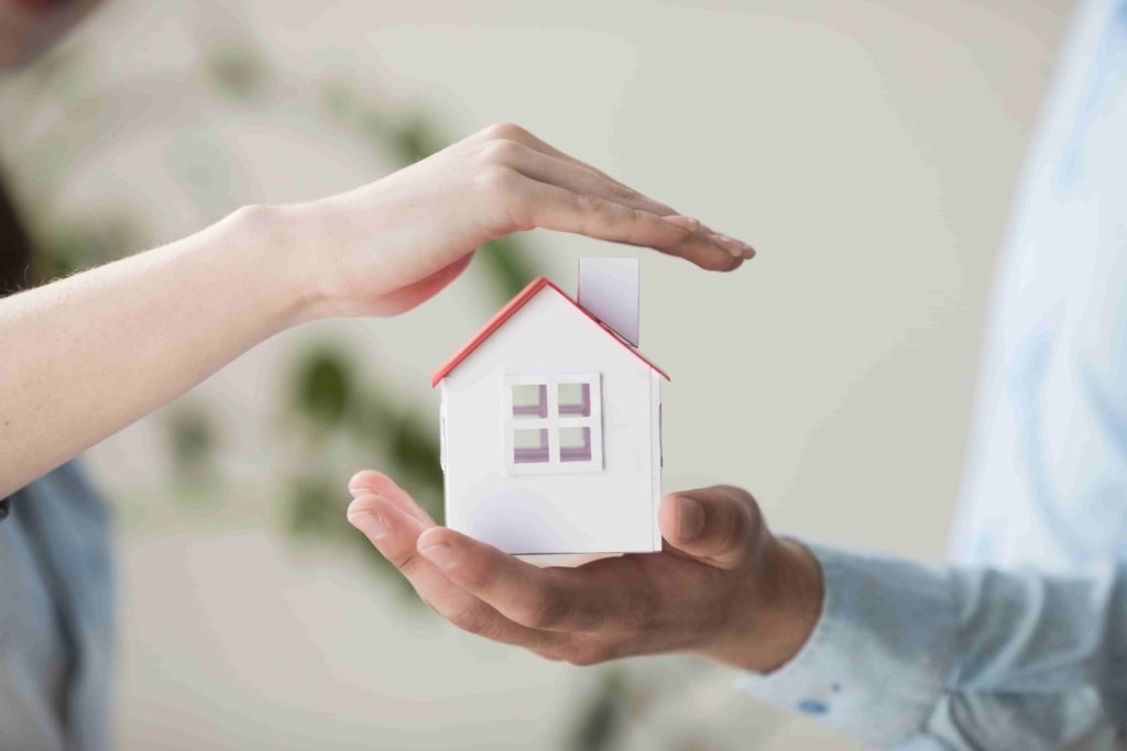 Image de deux mais protégeant une maison en papier - assurance emprunteur